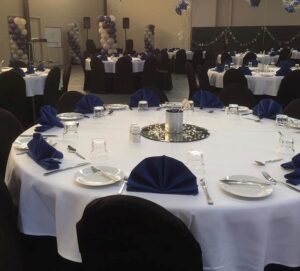 Function room with round tables dressed in white and navy at The Henry Parkes Motel