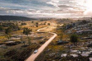 Car travelling a winding dirt road through granite country on Mount Mackenzie Drive at dusk