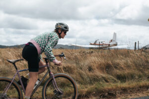 Gravel cyclist passing an old plane wreck on Black Swamp Road, Tenterfield