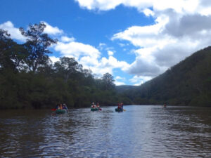 Kayakers paddling the calm Clarence River between forested hills